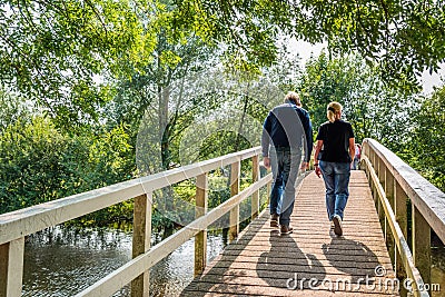 Man and woman walking over a simple wooden bridge Editorial Stock Photo