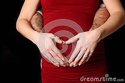 Man and womans hands on pregnant belly forming a heart Stock Photo