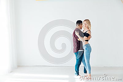 beautiful man and woman dancing bachata to music in a white room Stock Photo