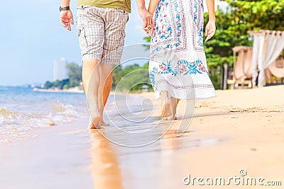 Man and women hold one`s hand on the beach and front of sunset. they are couple. they are walking on the sand and water Stock Photo