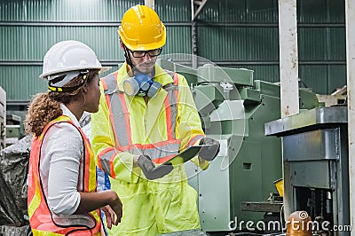 Man and women Industrial engineers wearing safety uniform and hard hats with tablet working heavy industry. Stock Photo