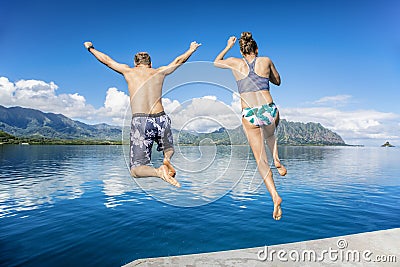 People jumping into the ocean while on a beautiful scenic Hawaiian vacation Stock Photo