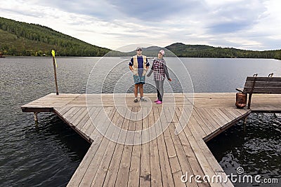 Man and women Tourists at the pier on the beautiful Ural Lake Teren Kul against the background of the Ilmensky ridge. Stock Photo