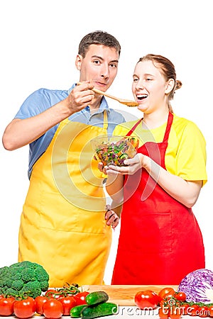 a man with a wooden spoon feeds a girl with a useful vegetable salad on a white Stock Photo