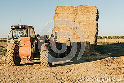 a man in work clothes preparing feed to be transported on a tractor Stock Photo