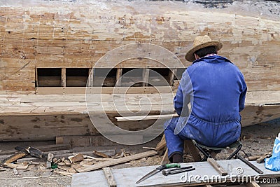 Man with work overalls fixing a wooden boat Stock Photo