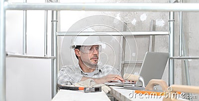 Man work, professional construction worker with computer, plastering tools on scaffolding, safety hard hat, gloves and protective Stock Photo