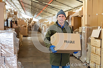 Man worker carrying cardboard box with fragile content Stock Photo