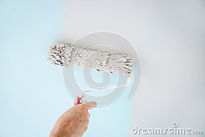 Man worker using paint roll to repaint old wall paint, rolling tool. Stock Photo