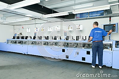 Man working on a brochure and magazine stitching process machine Editorial Stock Photo