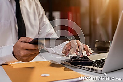 The man working on calculator to calculate financial data report, accountancy document and laptop computer at office. Stock Photo