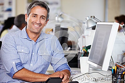 Man Working At Desk In Busy Creative Office Stock Photo