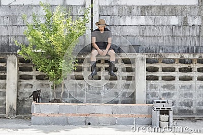 Man working in garden sitting and watching black cat Stock Photo