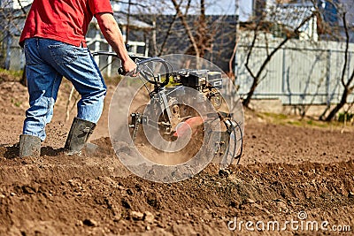 Man working in the garden with Garden Tiller Stock Photo