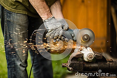 Man working with grinder saw, close up view on tool. Electric saw and hands of worker with sparks. Worker cutting metal Stock Photo