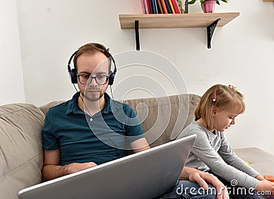 Man working from home on his computer while his daughter is playing. Stock Photo