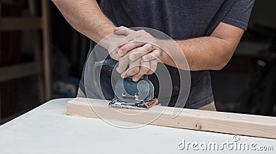 A man working on a home improvement project sanding wood with an electrical sander. Stock Photo