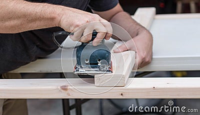 A man working on a home improvement project sanding wood with an electrical sander. Stock Photo