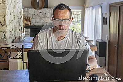 A man working at home, using a laptop computer, using internet, reading news, doing online shopping order for delivery, or Stock Photo