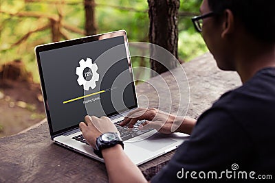 Man working and Installing update process with gearbox percentage progress and loading bar on laptop / computer Stock Photo