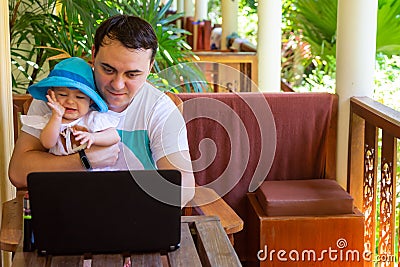 Man working with notebook in travel. Father with infant on hands. Work and baby care Stock Photo