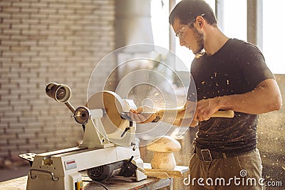 Man working at small wood lathe, an artisan carves piece of wood Stock Photo