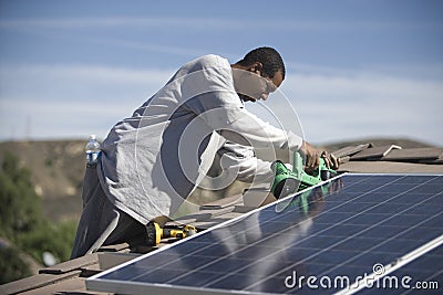 Man Working On Solar Panelling On Rooftop Stock Photo