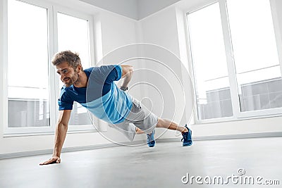 Man Workout Exercises. Fitness Male Model Doing Push Ups Indoors Stock Photo