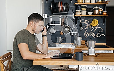 Man works at a laptop in the interior of a home decor in the kitchen. Remote work Stock Photo