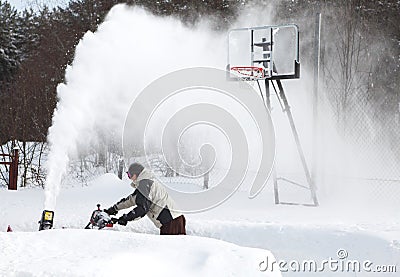 A man works snow blowing machine Stock Photo