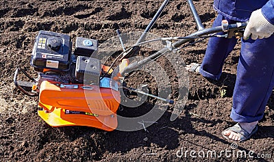 A man works in a vegetable garden in early spring. Digs the ground. Works as a cultivator, walk-behind tractor Stock Photo