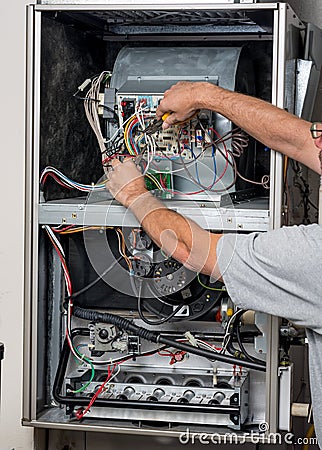 Handyman does furnace repair with tools Stock Photo
