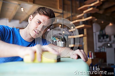 Man In Workshop Upcycling And Working On Furniture With Sandpaper Stock Photo