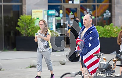 A man wrapped in a towel with an image of the American flag is walking down the street Editorial Stock Photo