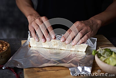 Man wraps a durum or a burrito in aluminum foil Stock Photo