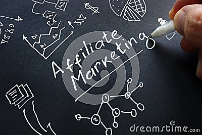 Man is writing Affiliate marketing on a black surface Stock Photo