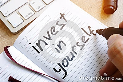 Man is writing invest in yourself. Stock Photo