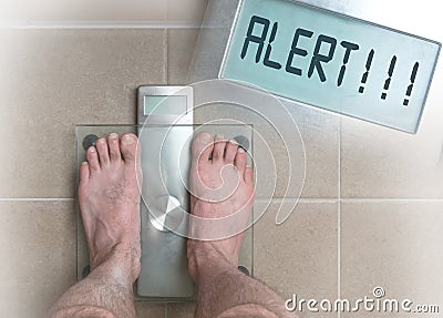 Man& x27;s feet on weight scale - Alert Stock Photo