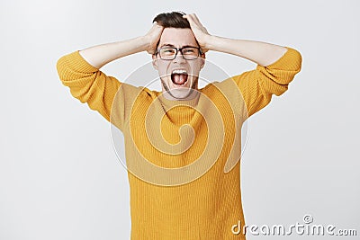 Man yelling cannot control panic and stress holding hands on head open mouth and screaming out loud from distress and Stock Photo