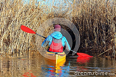 Man in a yellow kayak rowing through the aisle in a dry cane Stock Photo