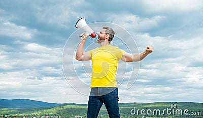 man in yellow shirt announcing in megaphone on sky background Stock Photo