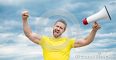 man in yellow shirt with loudhailer on sky background Stock Photo