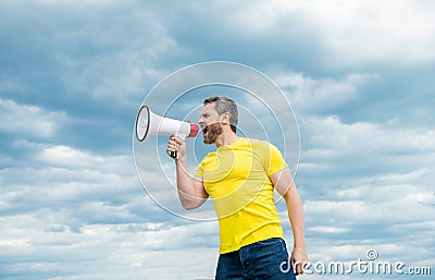 man in yellow shirt shout in megaphone on sky background. proclaim Stock Photo