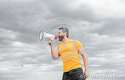 man in yellow shirt shout in megaphone on sky background. proclaim Stock Photo