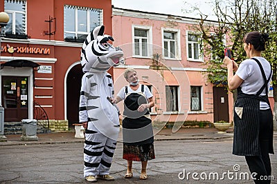 A man in a zebra costume on a city street embraces and takes photos with passers-by. Advertising on the street. Work in advertis Editorial Stock Photo