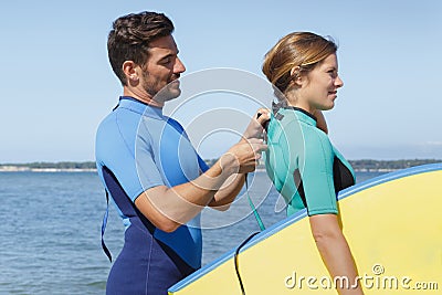 Man zipping up girlfriends wetsuit Stock Photo