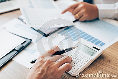 Manager calculates about the company finances by pressing on the calculator on the table with the employee explaining the summary Stock Photo