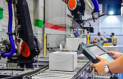 Manager check and control automation robot arms holding a white box and worker operating a robot machine Stock Photo