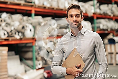 Manager standing with an inventory clipboard on a warehouse floor Stock Photo