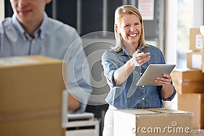 Manager Using Tablet Computer In Distribution Warehouse Stock Photo